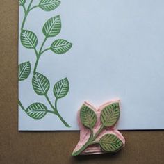 a piece of paper with leaves on it next to a rubber stamp that has been cut into the shape of a flower