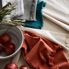 a white bowl filled with apples on top of a table next to an orange towel