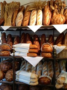 breads and loaves are displayed on shelves in a bakery setting with white napkins