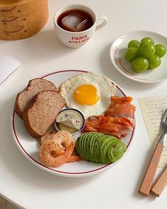 a plate with eggs, bread and vegetables on it next to a cup of coffee