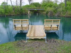 a couple of wooden benches sitting on top of a river next to a lush green forest