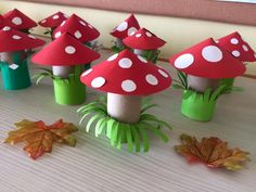 paper mushrooms are sitting on top of fake grass and leaves in the shape of trees