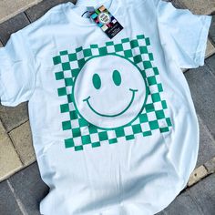 The CHECKERED SMILEY T-Shirt is made on unisex white, cotton tees. Coloring of checkered background is Green-Blue (aka Cyan). SIZING: Gildan G500 Adult Heavy Cotton T-Shirts are made of 100% preshrunk cotton.  Due to the nature of UNISEX tees, they may run a bit larger than expected.  Be sure to look at the provided size chart to guarantee the best fit for you.  APPAREL CARE: To ensure longevity of your t-shirt/crewneck/sweatshirt/tank:  1. Wash and dry garment inside out. 2. Use mild detergent Casual Plaid Cotton T-shirt, Casual Plaid T-shirt With Graphic Print, Casual Plaid Short Sleeve T-shirt, Checkered Background, Inside Out 2, Heat Transfer Design, Checker Print, Checkered Shirt, Streetwear Tshirt