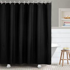 a black shower curtain in a bathroom with white tile flooring and gray walls, along with a wooden stool