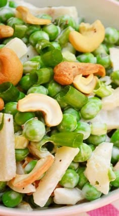 a bowl filled with peas and cashews on top of a checkered table cloth