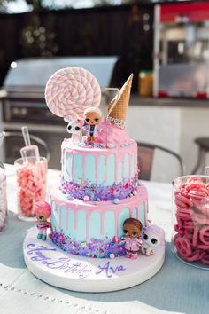 a three tiered cake with candy and lollipops on the table next to it