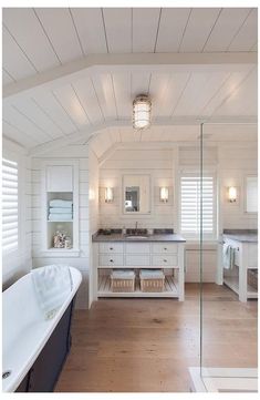 a large white bathroom with wooden floors and walls, along with a freestanding bathtub