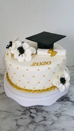 a graduation cake decorated with white flowers and gold trim