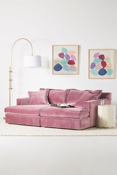 a living room with a pink couch and two pictures on the wall above it, along with a white rug