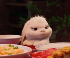 a white stuffed animal sitting at a table with plates of food in front of it