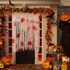 halloween decorations with pumpkins and candles in front of a door decorated with blood on it