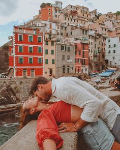 a man kissing a woman on the cheek in front of a city with red buildings