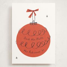 an orange christmas ornament with the words peek the balls below it and red ribbon on top