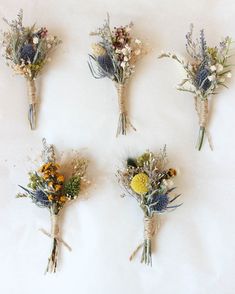 four bouquets of dried flowers are arranged on a white surface