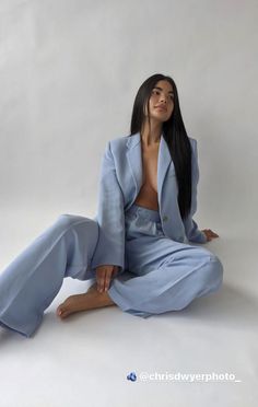 a woman sitting on the ground wearing a blue suit