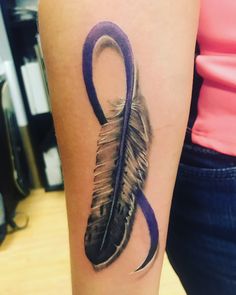 a woman with a tattoo on her arm has a purple ribbon and an arrow in the shape of a feather