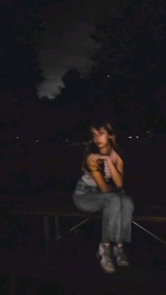 a woman sitting on a bench in the dark