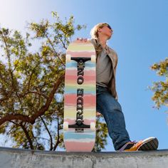 a skateboarder standing on the edge of a concrete wall with trees in the background