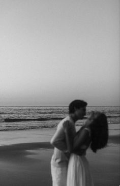 black and white photograph of two people kissing on the beach