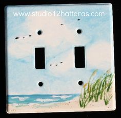 an artistic light switch cover with sea grass and birds painted on the wall next to it