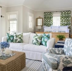 a living room filled with white furniture and lots of green pillows on top of it