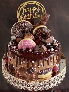 a birthday cake with chocolate frosting, sprinkles and donuts on top