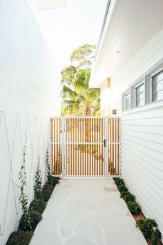 an entrance to a house with white walls and wood slats on the fence,