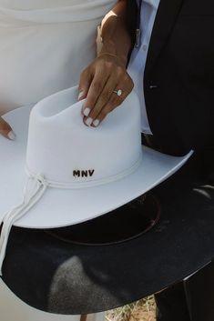 a man in a suit and tie holding a white hat with writing on the brim