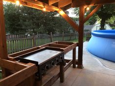 an outdoor kitchen under a pergolated roof with lights on the top and bottom