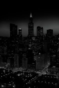 black and white cityscape at night with skyscrapers lit up in the distance