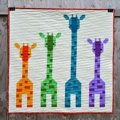 a quilted wall hanging with three giraffes on it's side