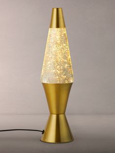 a gold colored lamp with white glitter on it's side and a black cord