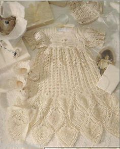 a baby's crochet dress and bonnet are laying on the ground next to other items