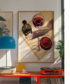 two wine glasses sitting on top of a table next to a blue lamp and record player