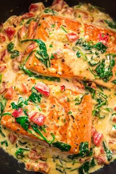 two cooked salmon fillets in a skillet with spinach and cheese on top