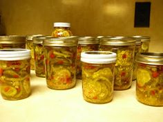 several jars filled with pickled vegetables sitting on a counter top next to each other