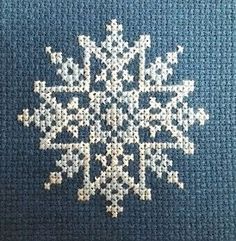 a cross - stitch snowflake is shown on a blue background with white dots