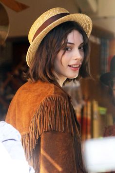 a woman wearing a hat and fringe jacket