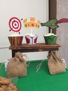 some cupcakes are sitting on a table with paper hats and arrows in them