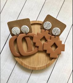 three pieces of clay sitting on top of a wooden board next to buttons and magnets