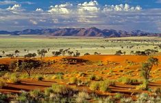 the desert is full of sand dunes and mountains in the distance with blue skies above