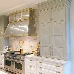 a kitchen with marble counter tops and stainless steel range hood over an oven, built - in cabinets