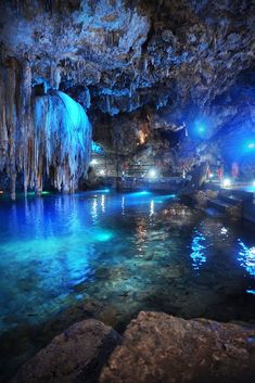 the inside of a cave filled with blue water and lit up by bright colored lights