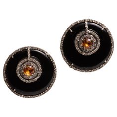 A pair of round stud earrings of black onyx with a round, faceted orange sapphire and both bordered with pave`-set round, brilliant cut diamonds. Set in sterling silver with an 18K gold post for pierced ears. Diamonds total 1.3 carats, the black onyx total 20 carats and the sapphire is 6 carats. The fine jewelry collection is sourced, designed or created by Deborah Lockhart Phillips. Through her international travels, she has cultivated prime resources for fine precious and semi-precious gemstones of unusual cuts in a variety of settings. Included in the collection are antique, high 22K gold pieces with intricate workmanship rarely found in the modern age. In creating the contemporary collection, Deborah works directly with artists and craftsmen to bring cutting edge jewelry designs direct Black Stud, Orange Sapphire, Gold Piece, Round Stud Earrings, Fine Jewelry Collection, Precious Gemstones, Sapphire Diamond, 22k Gold, Pierced Ears