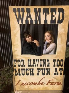 a man and woman standing in front of a sign that says wanted for having too much fun at lusciouse farm