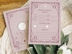 two pink wedding stationery cards sitting on top of a wooden table next to flowers