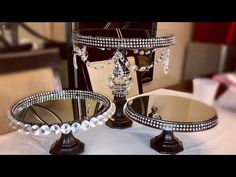 two mirrors sitting on top of a table covered in pearls and crystal beads, each with a diamond centerpiece