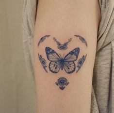 a blue butterfly tattoo on the right arm and shoulder, with flowers in the shape of a heart