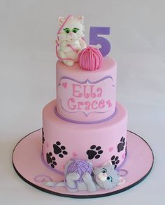 a pink cake with two cats on top and the number five in front of it