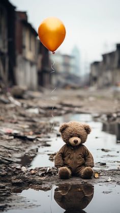 a teddy bear sitting on the ground with a balloon